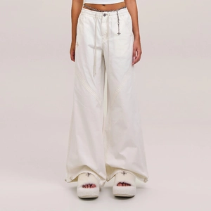 White high-waisted cargo pants with utility pockets and a decorative metal waist chain