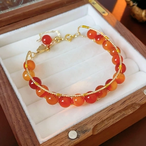 Detail of hand-woven orange tiger eye beads and golden wire on a luxury jewelry box