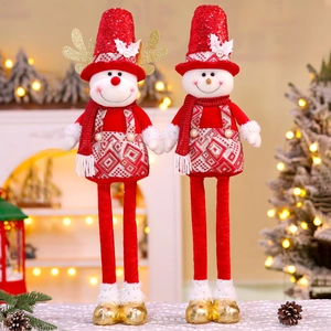 Détail de figurines de Noël en peluche à paillettes dorées et longues jambes près du feu
