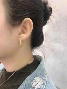 Close-up of minimalist polished gold hoop earrings worn with a casual outfit