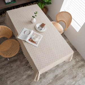 Close-up of beige linen tablecloth with yellow floral patterns and fringe details