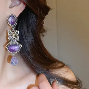 Vintage cat head drop earrings with purple stones and silver finish on model
