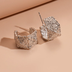 Minimalist square C-shaped earrings with molten silver texture on a warm beige background