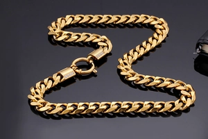 Detailed view of gold-plated Cuban link necklace with zircon-studded clasp on black surface