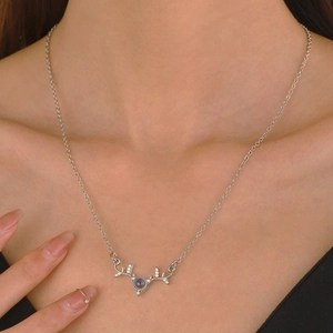 Macro shot of silver reindeer antler necklace with a round stone on model neck