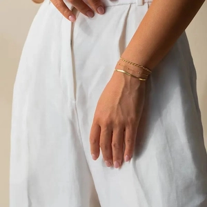 Minimalist gold-plated stainless steel layered chain bracelet set worn by a female model