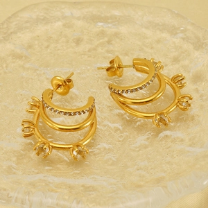 Vue détaillée des boucles d'oreilles triple anneau dorées serties de zircons brillants