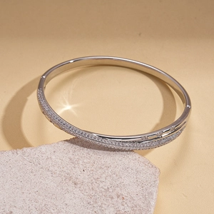 Detail showing pave-set white zircons on silver-plated bangle against stone texture