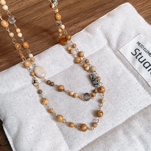 Detail of bohemian gold-plated beaded necklace with natural tiger eye and crystal stones
