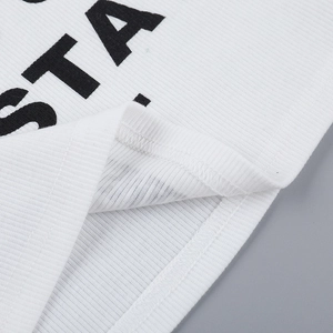 Close-up of white ribbed fabric detail with black STA lettering and double stitching