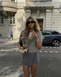 Close-up of grey slim-fit knitted short cardigan and wrap skirt in outdoor city setting