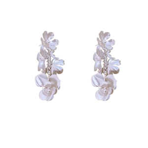 Boucles d'oreilles pendantes fleurs argentées avec pompon métallique sur fond blanc