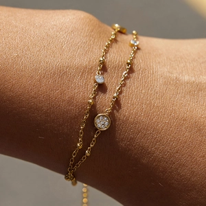 Primo piano di un bracciale a doppio strato in acciaio al titanio dorato con strass al polso