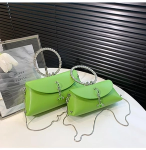 Detail of green handbag featuring sparkling rhinestone ring handles and silver chain strap