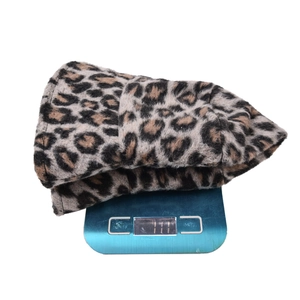 Cappello a secchiello leopardato pesato su una bilancia che mostra il peso di 111g