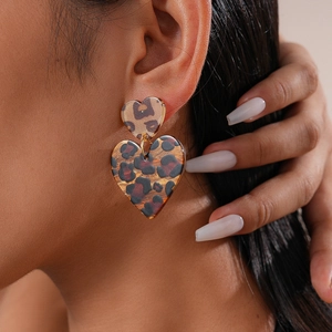 Close-up of vintage leopard print acrylic heart earrings worn by a model