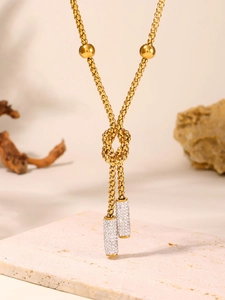 Detail of gold knot necklace featuring double crystal-encrusted cylinder pendants