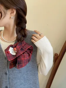 Detail of red and black plaid bow hair scrunchie with button and label on low ponytail