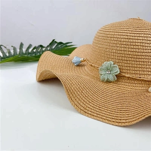 Macro shot of light beige straw hat featuring lace flower and sparkling rhinestone detail