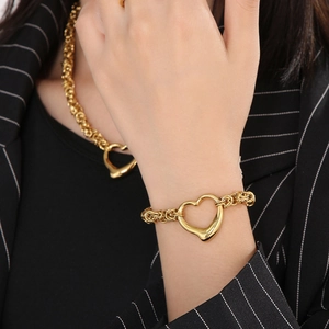 Close-up of golden braided heart necklace and bracelet set worn with a black blazer