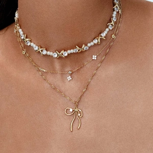 Three-layer gold-plated necklace with pearl X-links, clover charms, and bow pendant