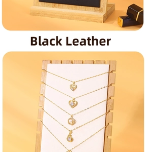 Detail view of gold-plated necklaces with heart pendants and pearls on a bamboo stand