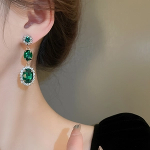 Detail of vintage emerald-green stone earrings with multi-layered gold metal setting
