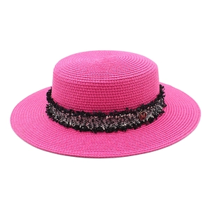 Detail of rose red straw boater hat featuring tweed ribbon and metallic M buckle