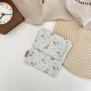 Close-up detail of a light blue floral mini storage pouch with a pink snap button
