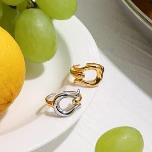 Polished two-tone and gold stainless steel open rings displayed on a white plate