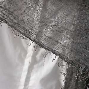 Macro shot of grey pleated linen fabric showing frayed fringe edges and soft texture