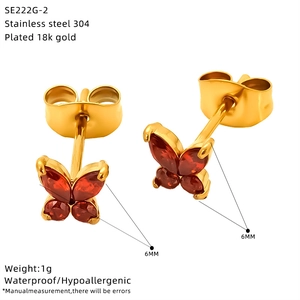 Detailed view of 6mm golden butterfly earrings with red stones and 18k gold plating