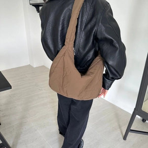 Brown padded puffer tote bag shown as a crossbody on a model in a casual outfit
