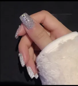 Macro shot of silver diamond glitter nail polish finish on fingers with white fur cuff