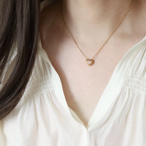 Minimalist 18K gold plated titanium necklace with a pink heart pendant worn by a model