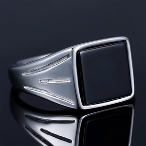 Macro detail of men's silver square signet ring with black gemstone and textured side