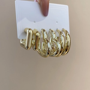 Gros plan de boucles d'oreilles créoles carrées et rondes dorées sur carte de présentation
