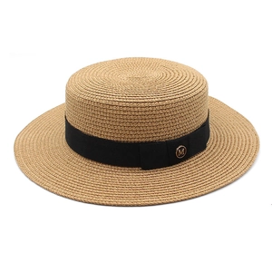 Détail d'un chapeau de paille élégant avec ruban noir et emblème logo M doré