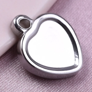 Macro shot of silver heart pendant base in 304 stainless steel on pink fabric