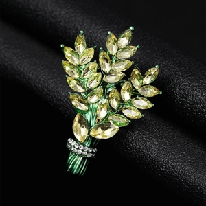 Macro view of crystal wheat ear brooch with green enamel stem and champagne gemstones