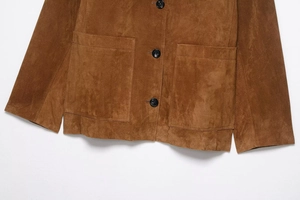 Close-up of brown faux suede jacket featuring black buttons and large patch pockets