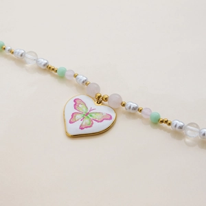 Gros plan du collier en or 18 carats avec perles et pendentif cœur papillon