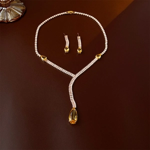 Detail of yellow pear-cut zircon necklace and earrings set on dark textured surface