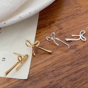 Macro detail of elegant bow-shaped stud earrings in gold and silver metallic finish