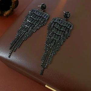 Detailed view of elegant black rhinestone tassel earrings on a premium leather box