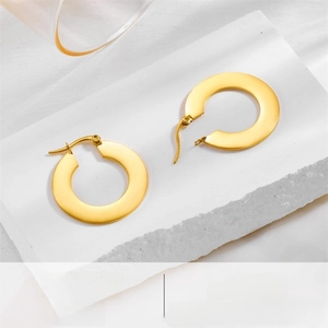 Macro shot of minimalist gold flat hoop earrings with a matte brushed metal texture finish