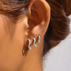 Detail view of s925 sterling silver wavy hoop earrings with clear gemstones on model