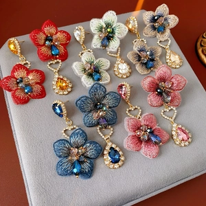 Détail de boucles d'oreilles vintage en fleurs brodées et cristaux sur un plateau en velours