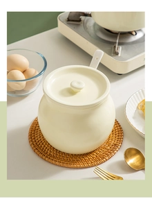 Macro shot of ceramic lard jar with lid and spoon on a woven rattan coaster