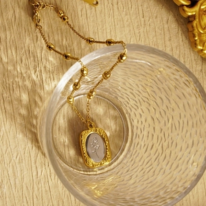 French retro rose pendant necklace with golden beaded chain on textured fabric